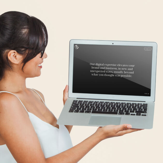 A woman holds a laptop displaying a message about enhancing brand and business using digital expertise, set against a neutral background.