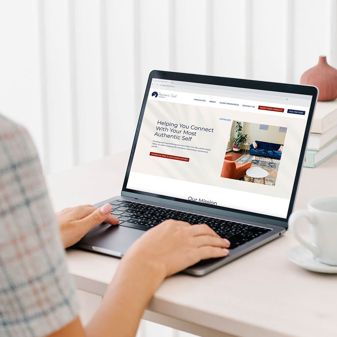 A person browsing Resilient Self Therapy’s website on a laptop, with a coffee cup nearby and a clean, modern workspace.