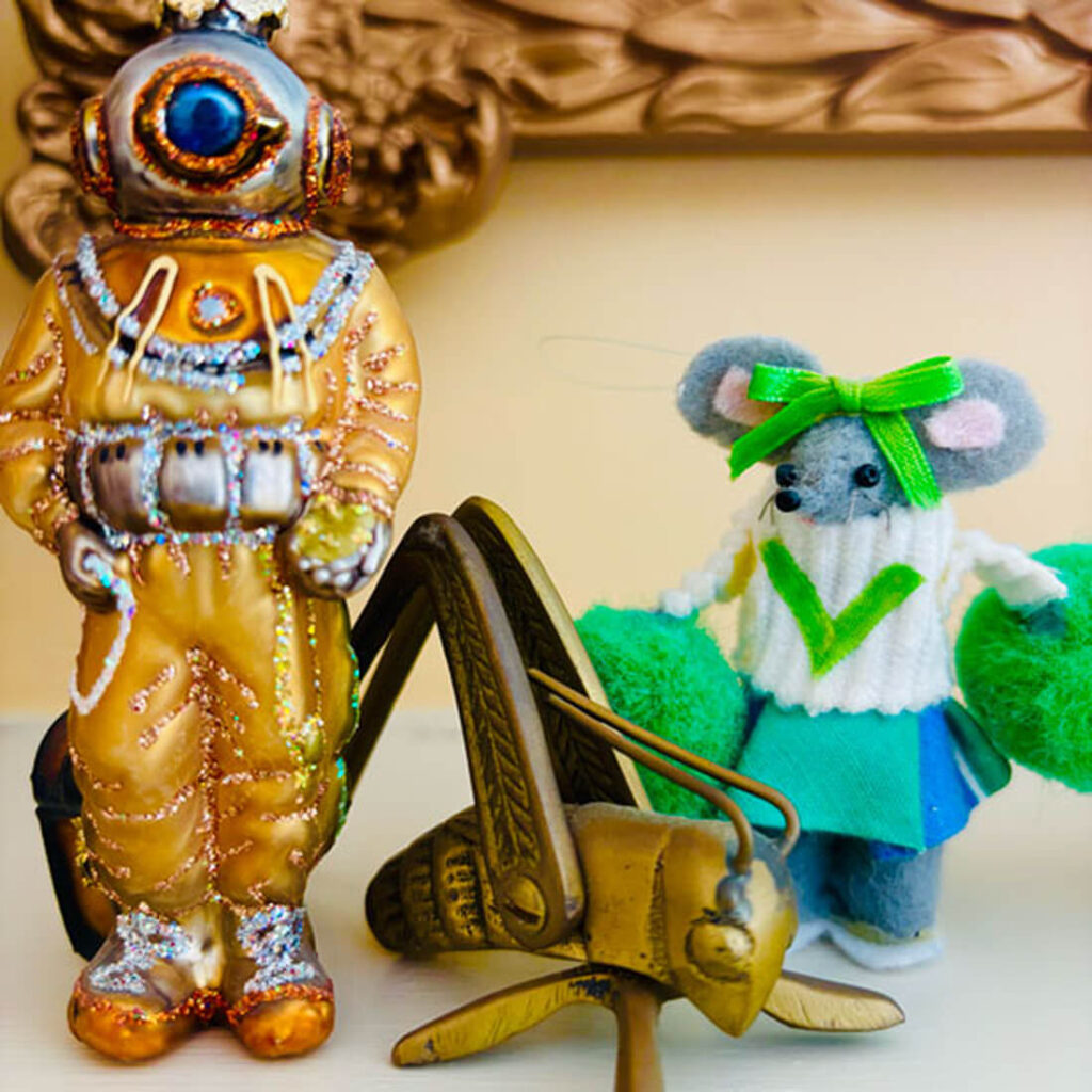 A decorative diver figurine stands next to a cute mouse doll in a green outfit, with a vintage grasshopper toy nearby.
